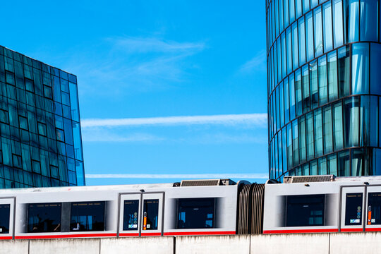 Urban train passing modern glass buildings in Vienna with blue sky and contemporary architecture creating a clean mobility and city transport scene