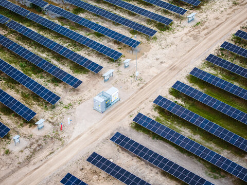 Aerial view of Tume Solar Park featuring rows of solar panels and a battery energy storage system unit situated along a dirt path in Tume Parish, Tukums Municipality, Latvia.
