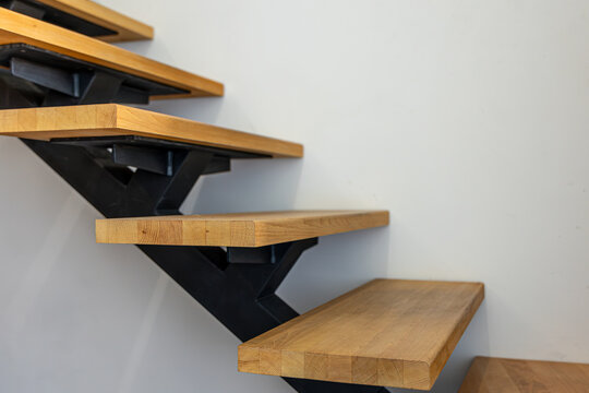 Wooden staircase with black metal stringer. Modern interior architecture detail.