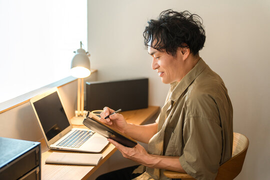 A middle-aged man working from home using a laptop computer.