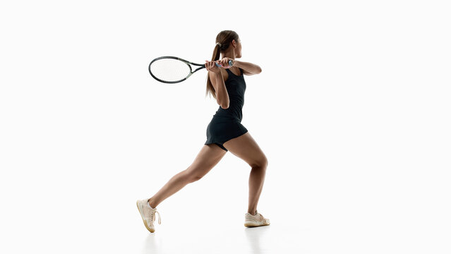 Female tennis player executing powerful two handed backhand on white background. Concept of backhand technique, stroke training, athletic control.