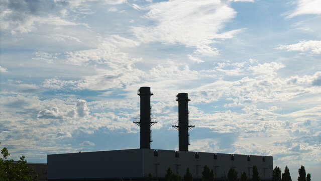 Aerial view of Spalding Power Station with its two prominent chimneys set against a dramatic sky with scattered clouds in Spalding, England, United Kingdom.