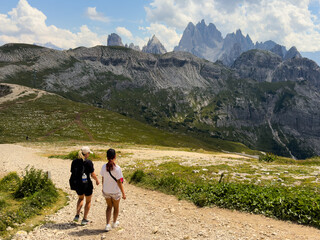 Naklejka premium People hiking a mountain trail with backpack in summer Dolomites Italy