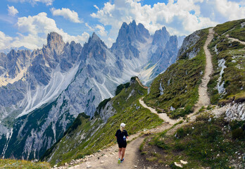 Naklejka premium Young woman exploring hiking trail in Dolomites near Tre Cime Dolomites Italy
