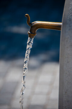 Bronze faucet pouring fresh water into a fountain