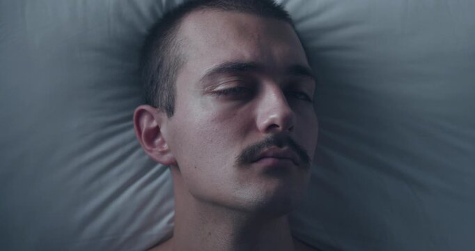 Top Down Portrait of Thoughtful Young Caucasian Man Lying Awake in Bed with Insomnia