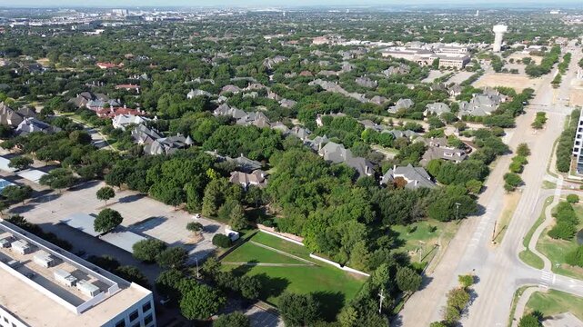 Expansive parking facilities border residential Starwood enclaves near Dallas Parkway. Towering tree barriers shield luxury properties from commercial activity across affluent Frisco, Texas