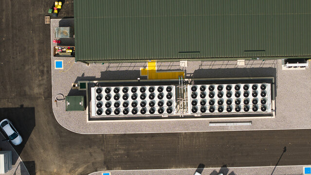 Aerial view of the National Grid Walpole Substation featuring rows of synchronous condenser cooling fans next to an industrial building with a green roof in Walpole, England, United Kingdom.