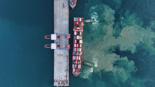 Container ship maneuvering at sea port terminal assisted by tugboats. Heavy cargo vessel docking for freight. Global maritime logistics, international shipping trade, and marine transport.