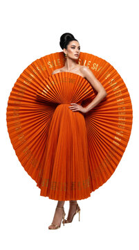Model wearing sculptural pleated orange fan dress with sale text isolated on transparent background.