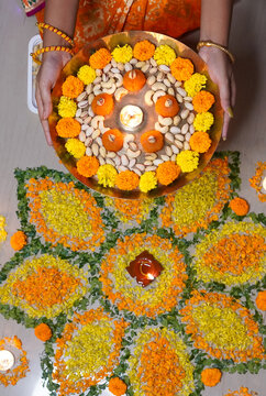 Indian girl holding hand flower plate for Diwali celebration by looking at camera at home concept of - Indian traditional, ceremony and festival preparation.