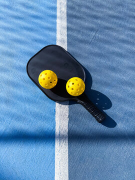 Pickleball paddle and balls resting on court line