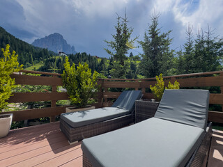 Naklejka premium Modern patio furniture with sofa. Overlooks rich green mountain landscape. Sunny day bright airy atmosphere. Perfect outdoor living space