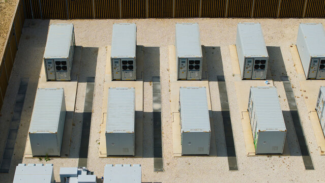 Aerial view of Bicker Fenn Battery Energy Storage Systems with rows of white industrial battery containers on gravel ground in Boston, England, United Kingdom.