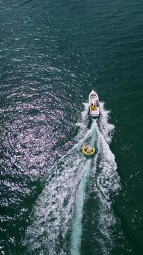 Aerial View of Speedboat Towing Inflatable Tube on Deep Blue Sea