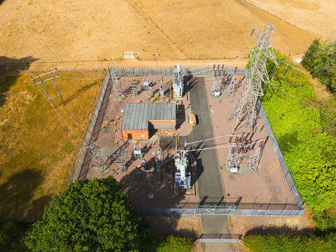 Aerial view of the Bourne West NGED 132kV Substation featuring electrical transformers, high-voltage power lines, and metal fencing in Bourne, England, United Kingdom.
