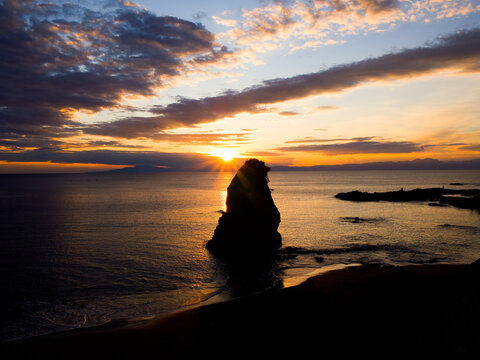夕日に照らされる海と岩礁のシルエットが美しい海岸風景