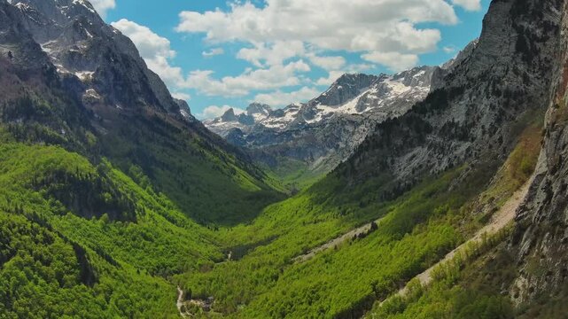 Aerial view of amazing rocky mountains in snow and green valley, Prokletie park, Montenegro and Albania, 4k