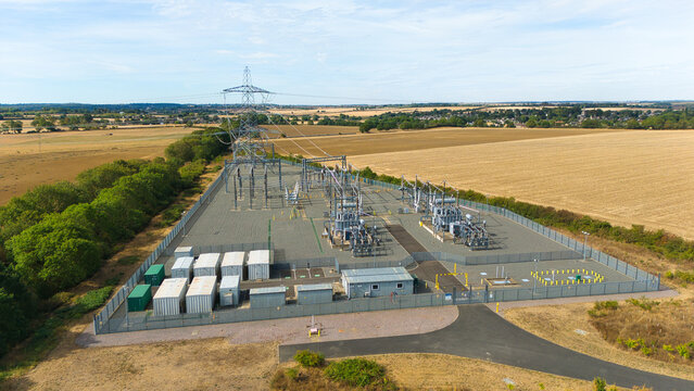 Aerial view of the National Grid Ryhall Substation 400kV featuring electrical infrastructure, high-voltage transmission towers, and a fenced compound in Ryhall, England, United Kingdom.