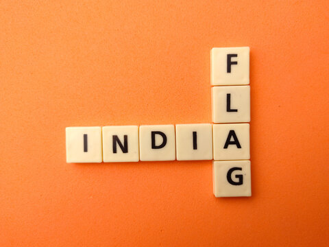 Plastic letter tiles arranged in an intersecting crossword grid spell INDIA and FLAG on an orange background