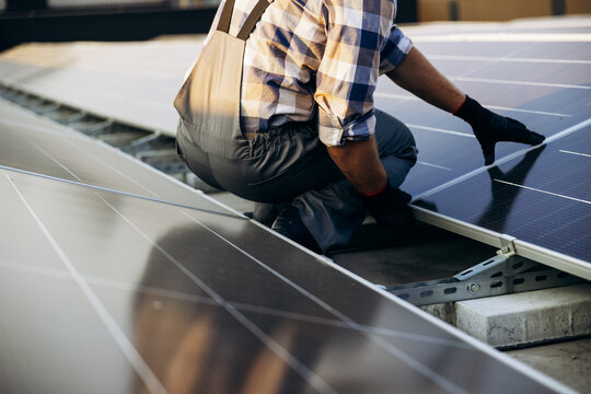 Technician installing photovoltaic solar panels on a rooftop, generating clean green energy for sustainable electricity production