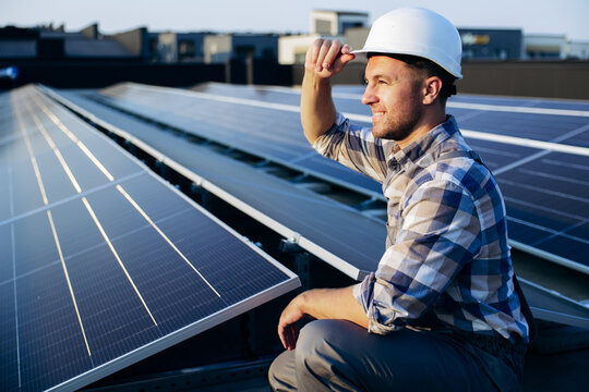 Smiling man installing solar panels, contributing to renewable energy production and sustainable power generation