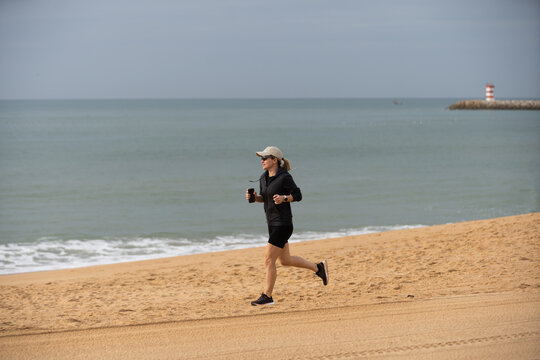 Young woman in shorts running on the beach. Girl runs to the coast, sports lifestyle