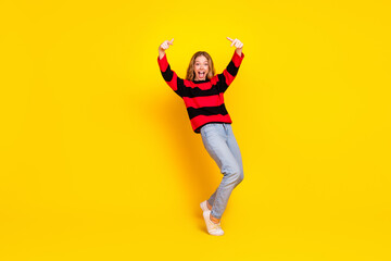 Charming young female in a striped pullover posing cheerfully against a bright yellow background...
