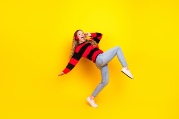 Naklejka premium Cheerful young woman enjoying music with bright headphones against a vibrant yellow background in casual stylish attire
