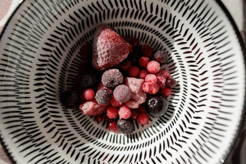 Mixed frozen berries sitting in patterned bowl © elbuenodehal