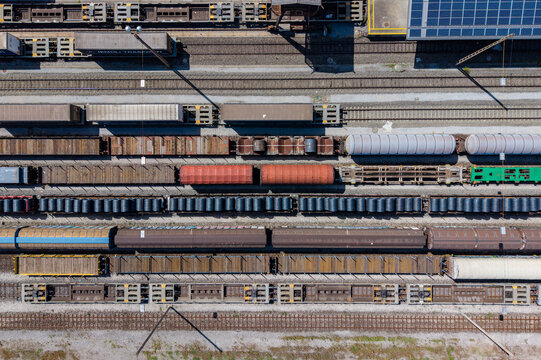 Aerial view of the Chiasso Cargo Train Terminal with various freight train cars lined up on multiple tracks, including flatcars, tank cars, and boxcars in Chiasso, Ticino, Switzerland.