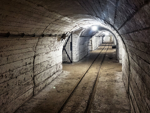 Inside of famous old tunnel with white wall, underground mine. The rough stone walls add to the dark, mysterious atmosphere of this abandoned passage