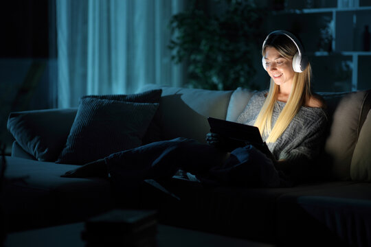 Woman in the night at home watching media on digital tablet
