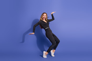 Young woman in striped jumpsuit poses energetically against blue background for fashion lifestyle...