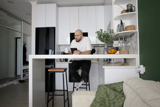 Resting Man Using Digital Tablet or Electronic Book Indoors. Surfing Internet Reading Electronic Book and Leisure Activity Concept