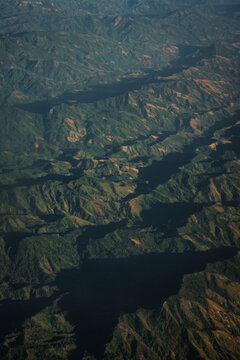 Aerial view of the rugged mountainous landscape featuring lush green hills, deep valleys, and dramatic shadows cast across the terrain in Madagascar.