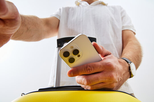 Man Holding Smartphone and Yellow Suitcase Ready for Travel