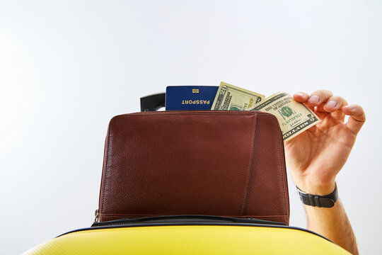 Traveler Hand Holding Dollar Cash and Passport with Suitcase and Leather Travel Bag