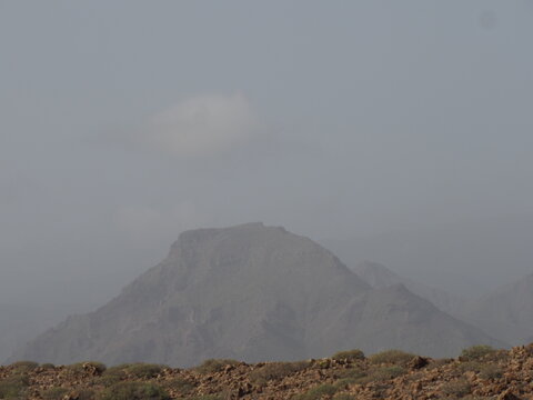 Majestic mountain peak shrouded in thick fog and mist during Calima weather