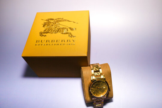 Lviv, Ukraine &ndash; August 30, 2026: An elegant gold-tone Burberry wristwatch lies on a cushion display next to its branded box. The stylish accessory features the signature plaid pattern on the bracelet 