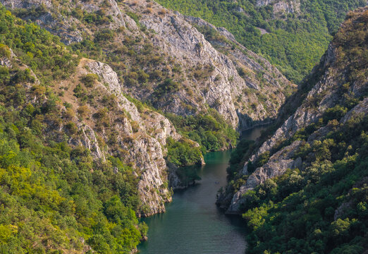 Aerial view of Matka Canyon featuring steep rocky cliffs, dense green forests, and the calm river flowing through the gorge in Skopje, Greater Skopje, North Macedonia.