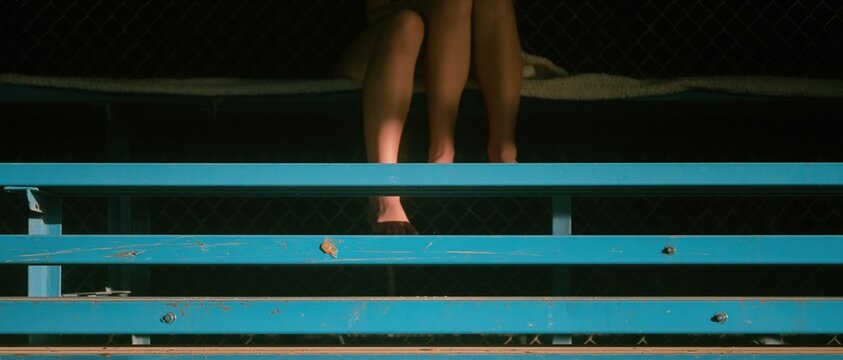 Blue painted metal bleachers with weathered textures and scuffed paint under stadium lighting for event marketing and sports backgrounds