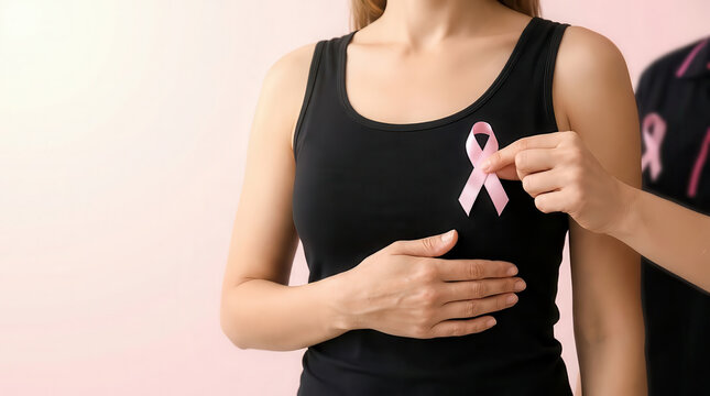 Woman holding a pink awareness ribbon against black clothing, breast cancer awareness and healthcare support concept, female health advocacy, prevention and solidarity campaign on light background