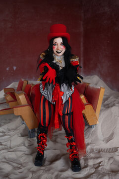 Circus performer standing on abandoned cinema seats with arms spread in commanding pose
