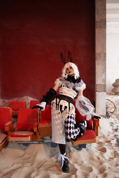 Thoughtful harlequin character resting hand near face on abandoned theatre seating