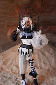 Avant garde harlequin costume with structured corset and tulle sleeves on sand dune