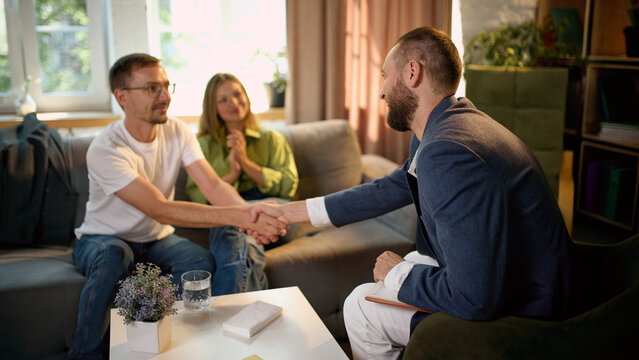 Male client shaking hands with family psychologist after successful couple consultation. Concept of therapy completion, professional agreement and positive outcome.