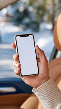 Hand holding smartphone with blank screen inside car during winter