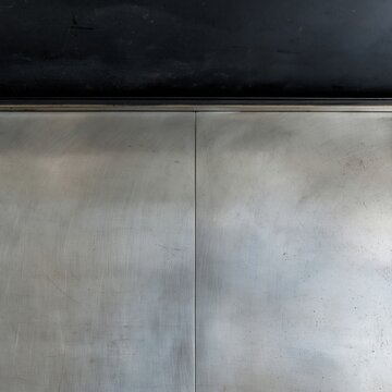 Brushed stainless steel splashback with a soot-darkened extraction hood, showing a worn greasy patina for food safety and quality control backgrounds