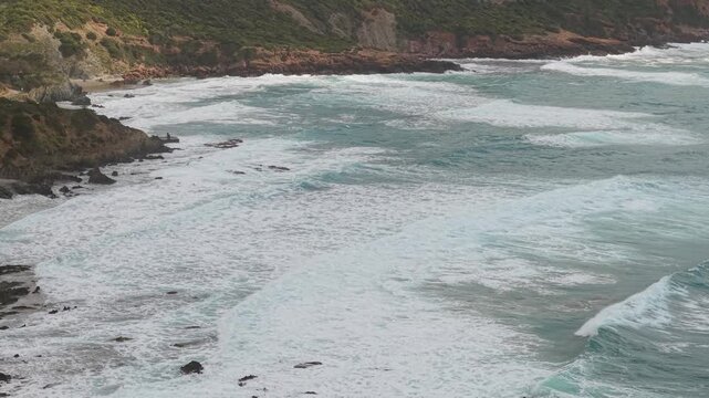 Waves Crashing Against Rugged Mediterranean Coastline Near Masua In Southwestern Sardinia, Italy. Aerial Slow-Motion Shot